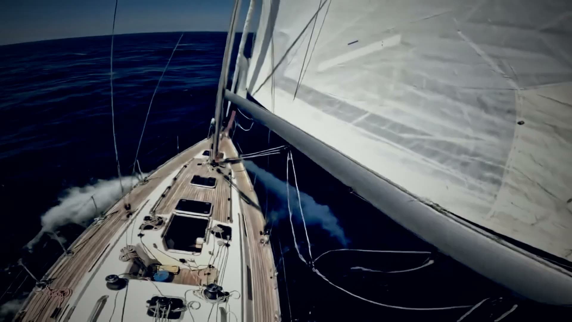 Deck view of a yacht under sail cutting through deep offshore swell